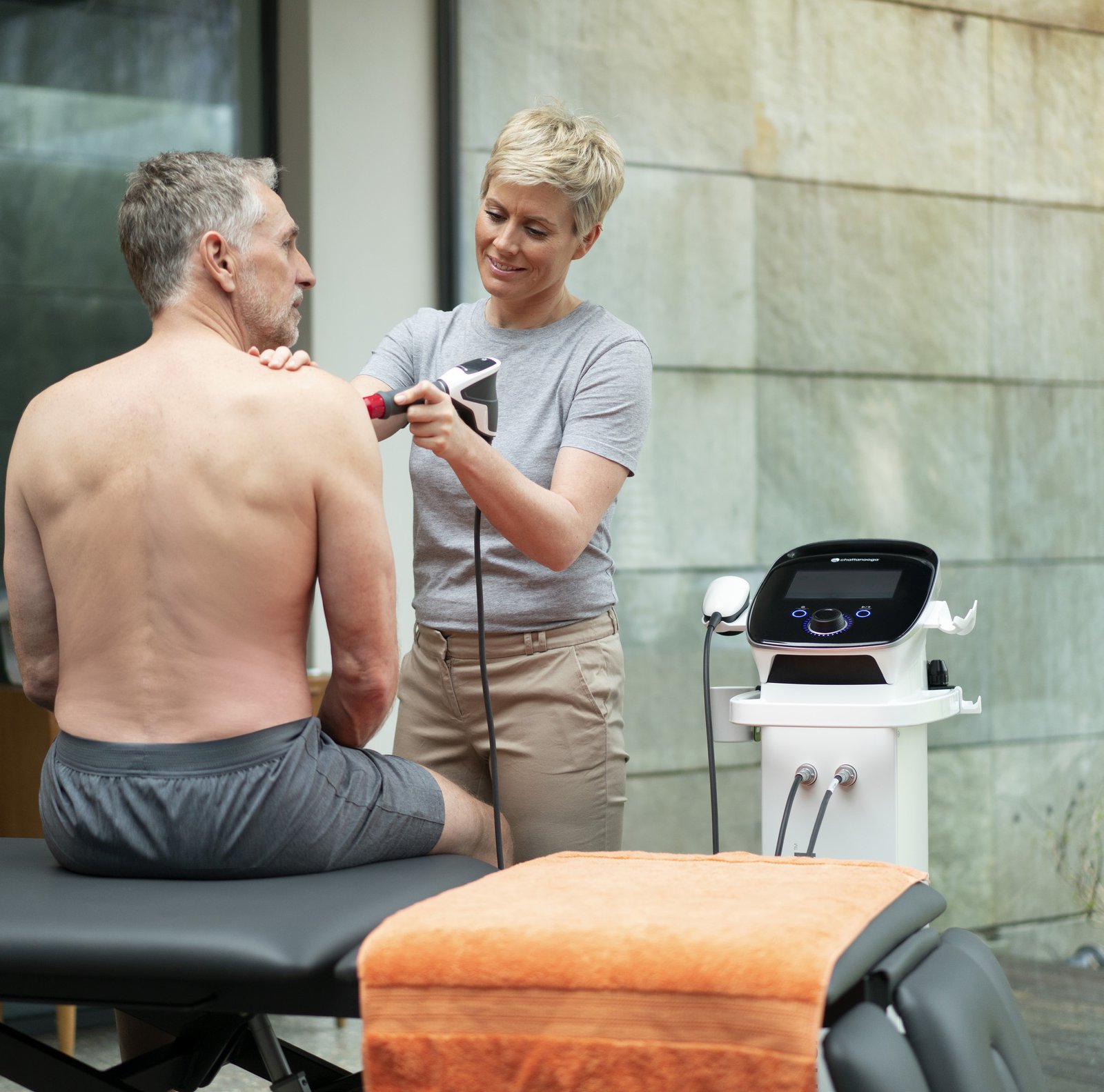 Fysioterapeut behandlar en patients axel med stötvåg under en Enovis-workshop